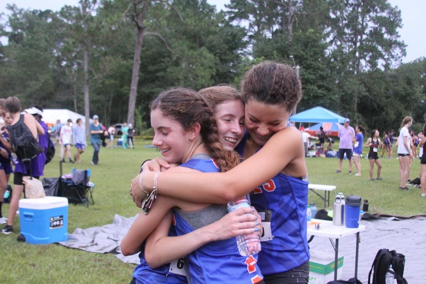 McClure located in the middle embraces her team after a race. 